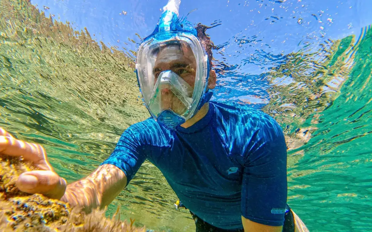 Man med snorkelmask njuter av snorkling i Thailand. Klart vatten och solljus skapar en magisk undervattensvärld.
