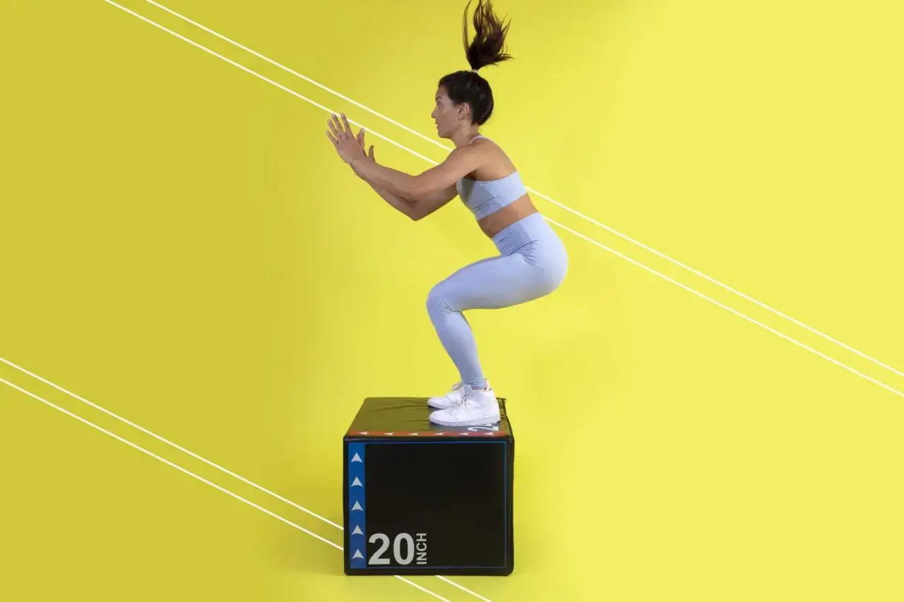 Frau macht Box Jumps auf einer schwarzen Box mit der Aufschrift 