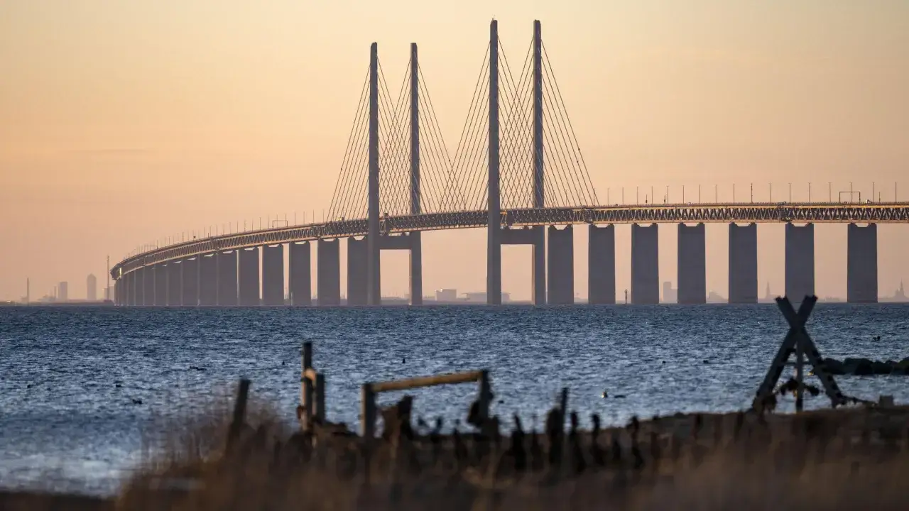 Stora Bältbron sträcker sig över det blå vattnet i solnedgångens gyllene ljus, en imponerande syn mot den mjuka himlen.