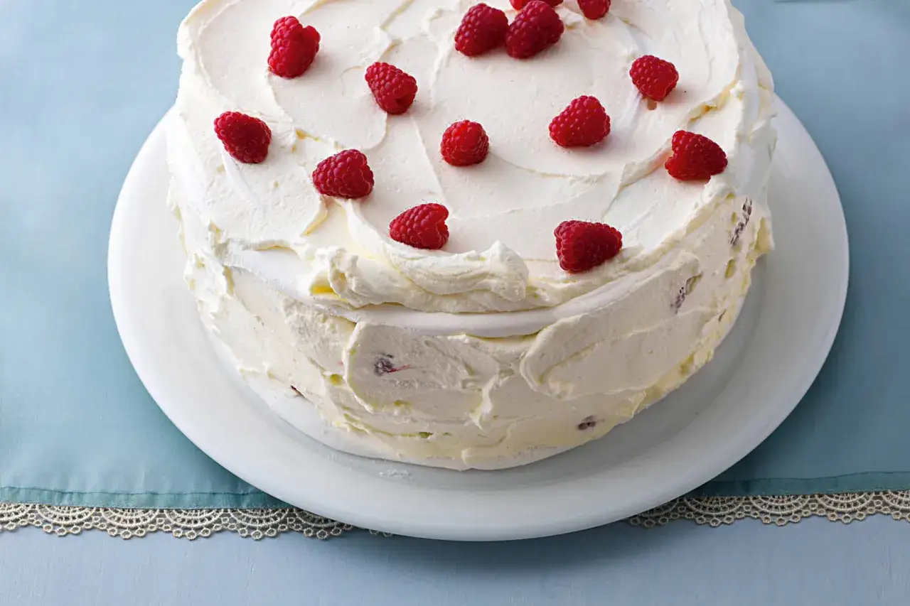 Ein üppiger Kuchen mit viel Sahne und frischen Himbeeren, der an einen süßen Eis-Baiser erinnert.
