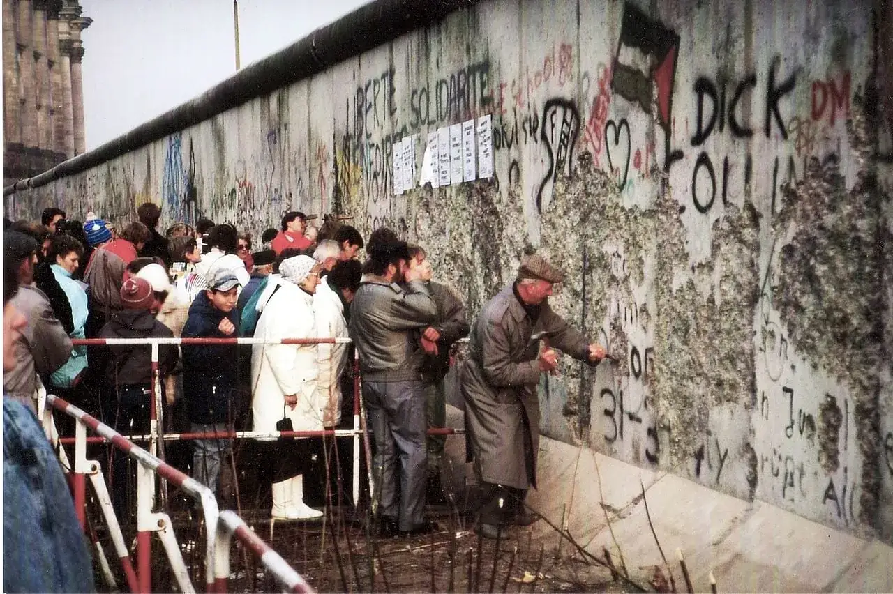 Ludzie przyglądają się i wykuwają fragmenty Muru Berlińskiego, gdy upadł mur berliński.
