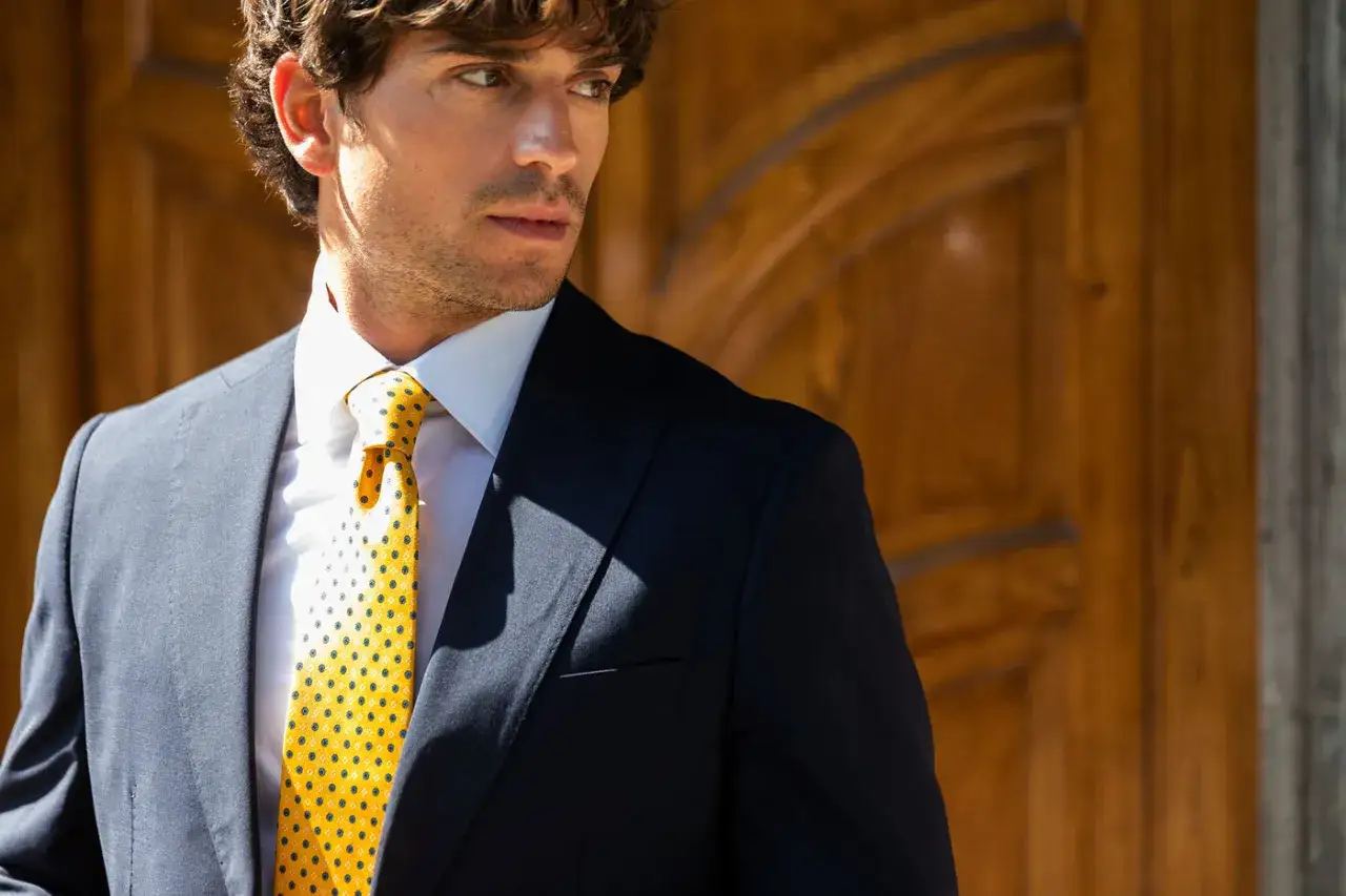 Uomo con cravatta gialla a pois, un esempio di come fare il nodo alla cravatta con stile.