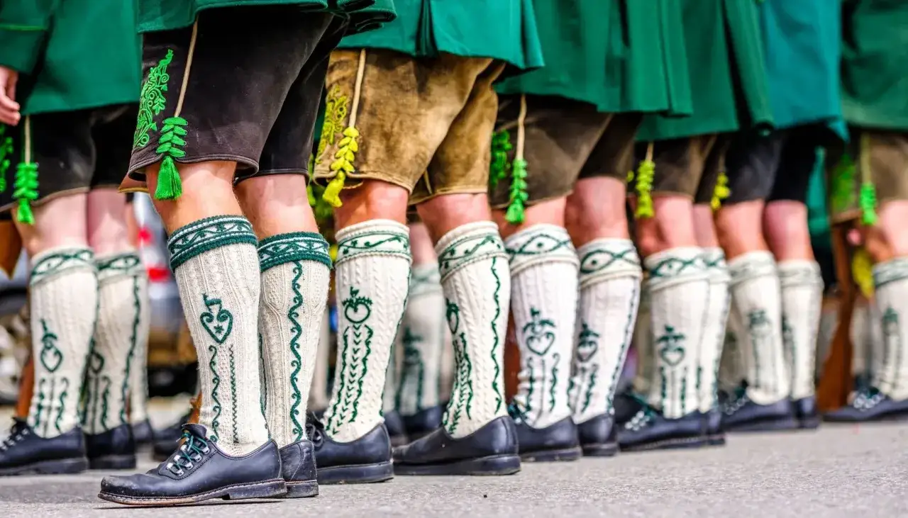 Herren in Lederhosen und traditionellen Strümpfen tragen schwarze Schuhe. Die Frage
