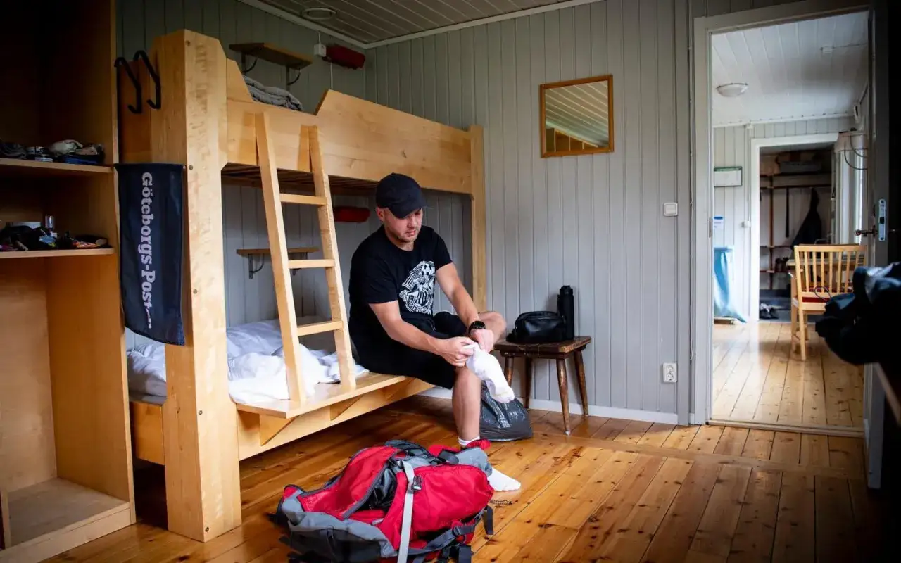 Man förbereder sig för vandring vid STF Kebnekaise. En röd ryggsäck ligger redo på golvet.