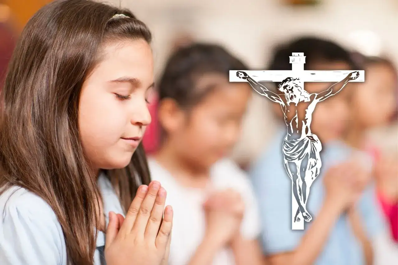 Dzieci modlące się na lekcji religii w szkole. W tle krzyż z Jezusem.
