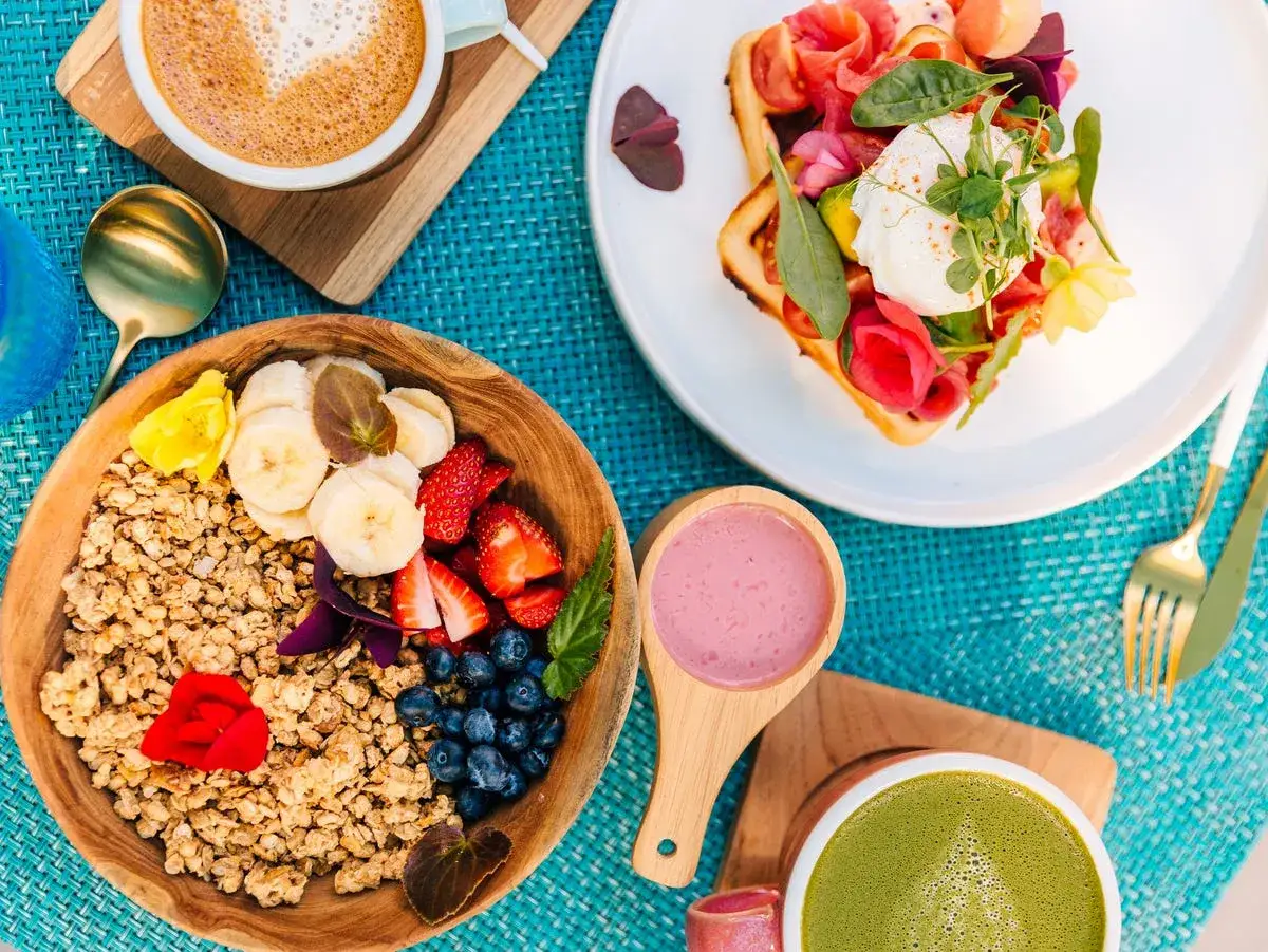 En h&auml;rlig frukost med granola, b&auml;r, banan, en v&aring;ffla med lax och pocherat &auml;gg, samt kaffe och matcha. Perfekta **desayunos saludables**!