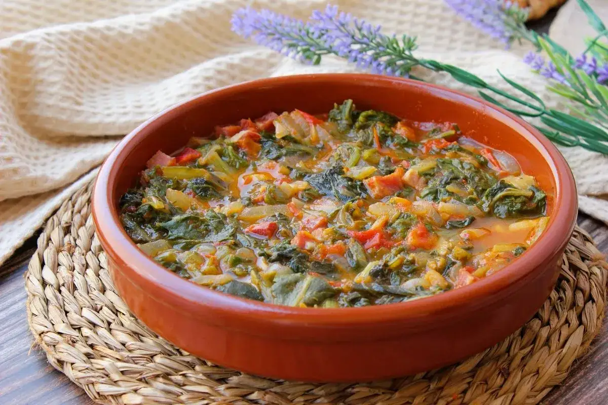 Un plato humeante de acelgas cocidas con tomate y cebolla, listo para servir.
