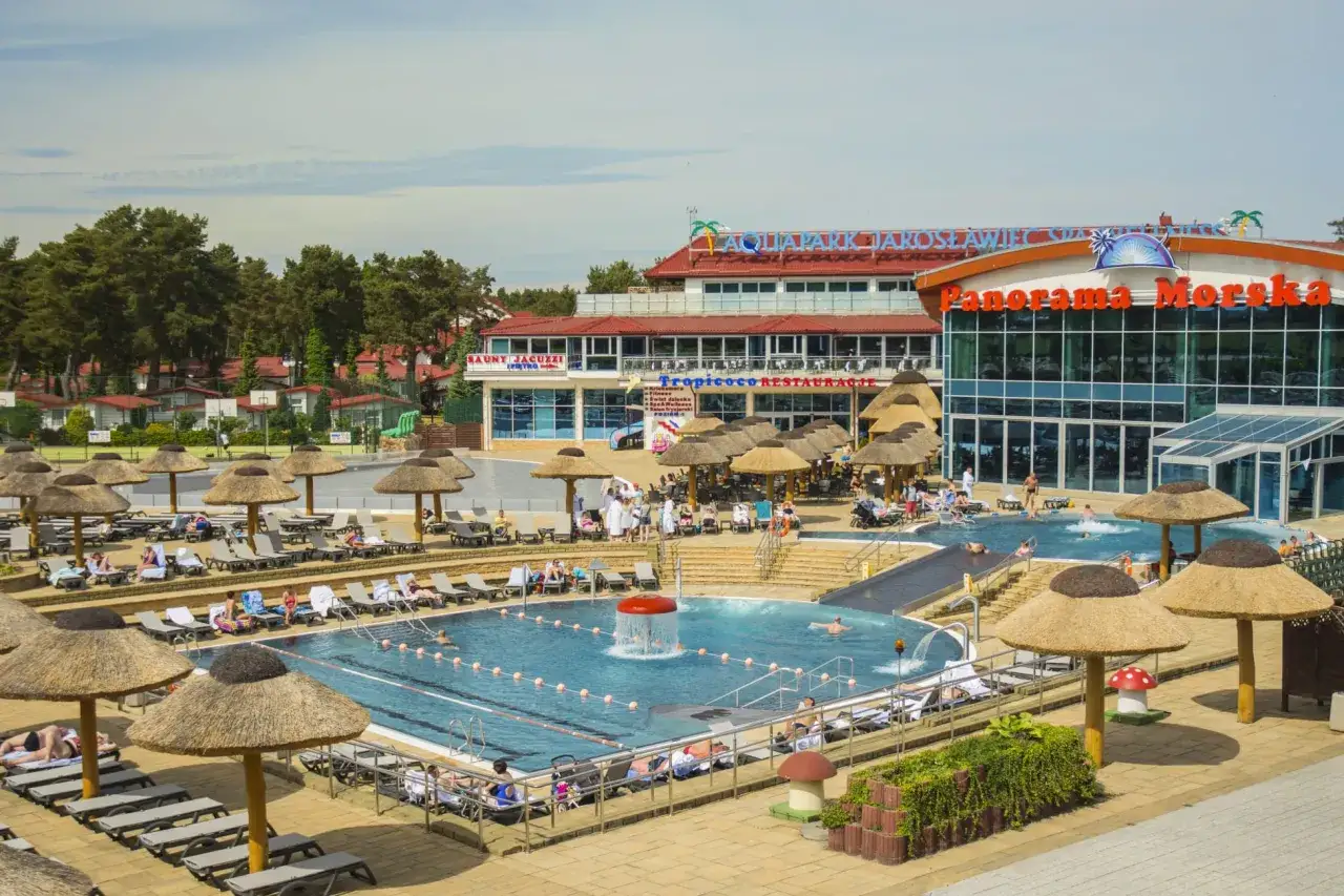 Hotel nad morzem z basenem all inclusive. Relaks przy basenie z parasolami i widokiem na budynek 