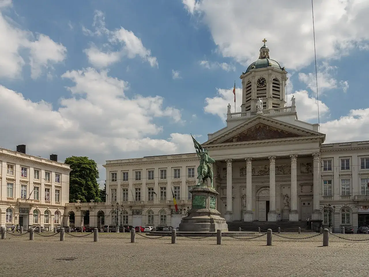 Estatua ecuestre frente a la imponente fachada de los Museos Reales de Bellas Artes de Bélgica, bajo un cielo nublado.