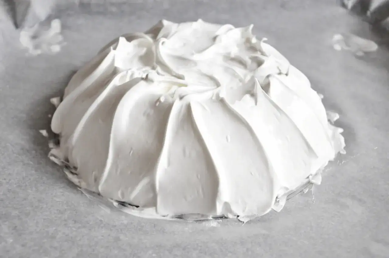 Idealna beza pavlova która zawsze wychodzi, przygotowana na papierze do pieczenia. Jej puszysta, biała masa tworzy efektowne fale.