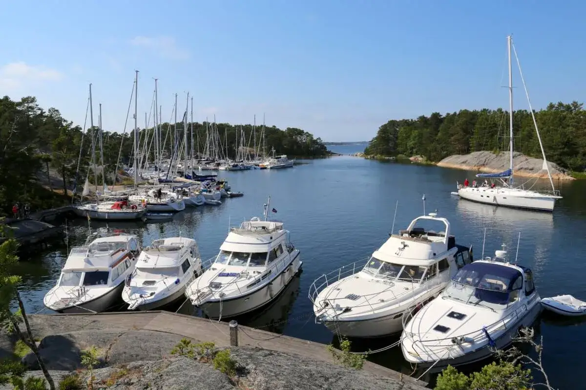 En solig dag vid Sandhamn camping, med många segelbåtar och motorbåtar i hamnen.