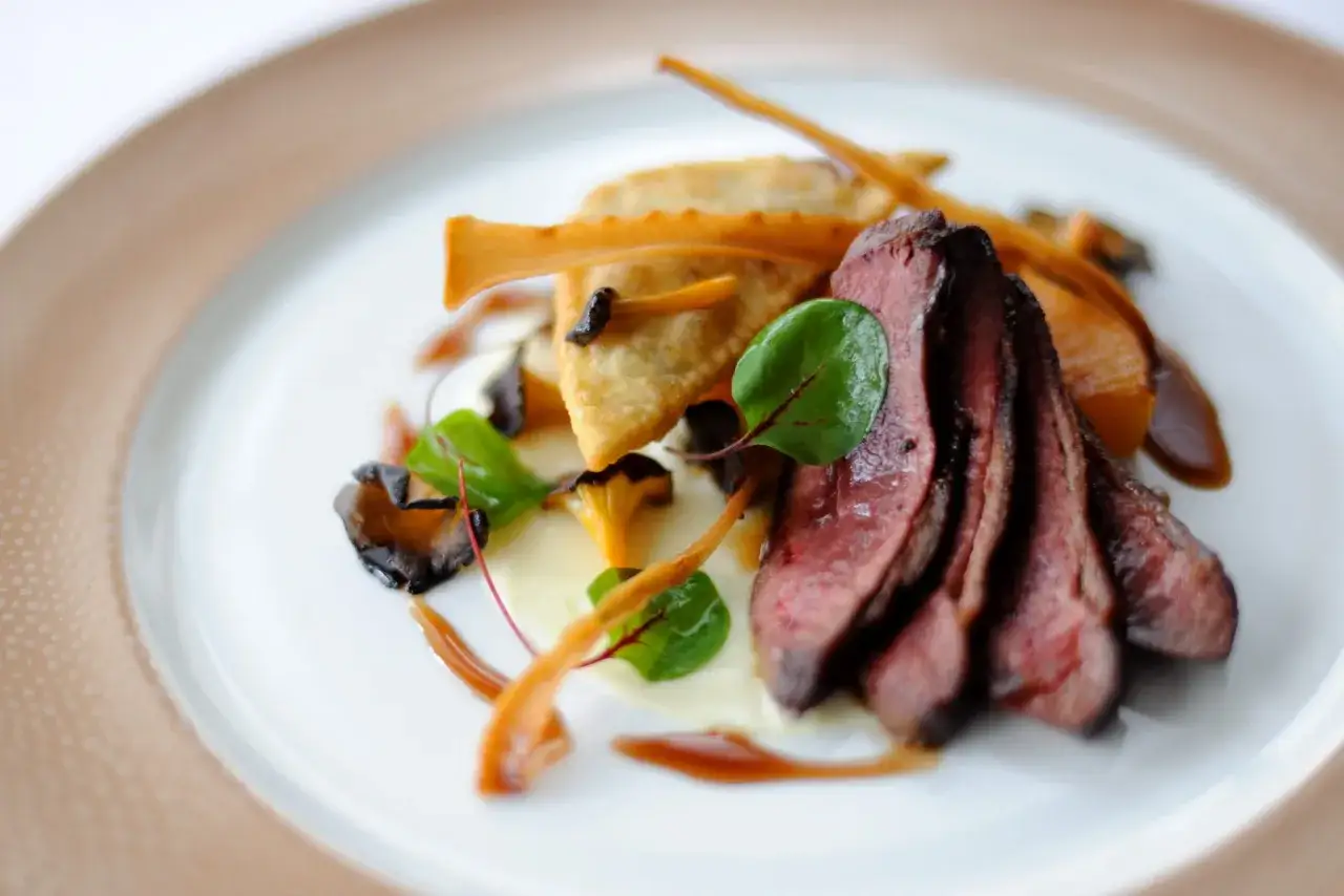 Une délicieuse entrée chaude de mariage : fines tranches de viande rouge, raviolis croustillants, champignons et purée onctueuse.
