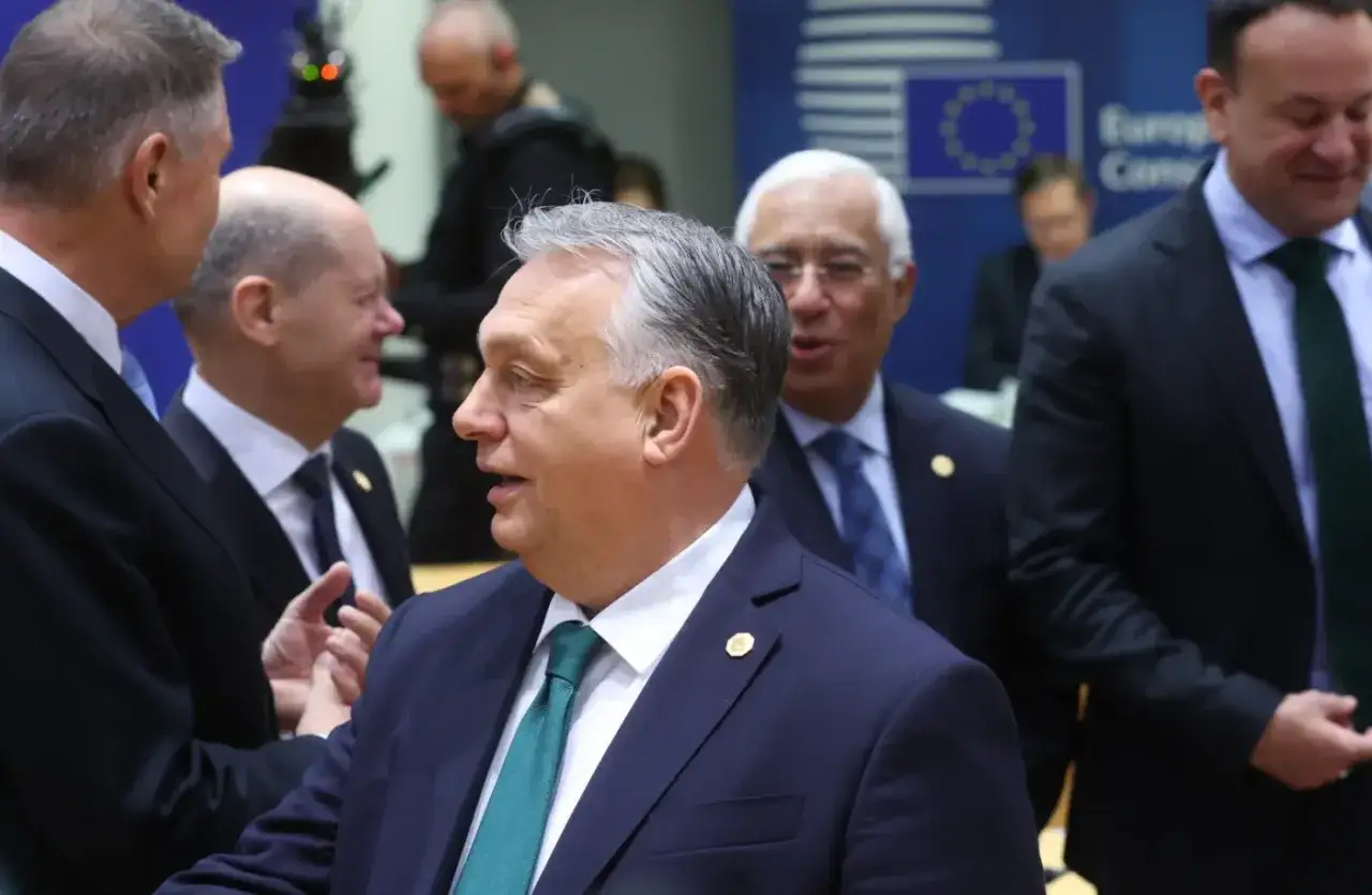 Viktor Orbán rozmawia z innymi politykami podczas spotkania w Brukseli. W tle widać flagę UE.