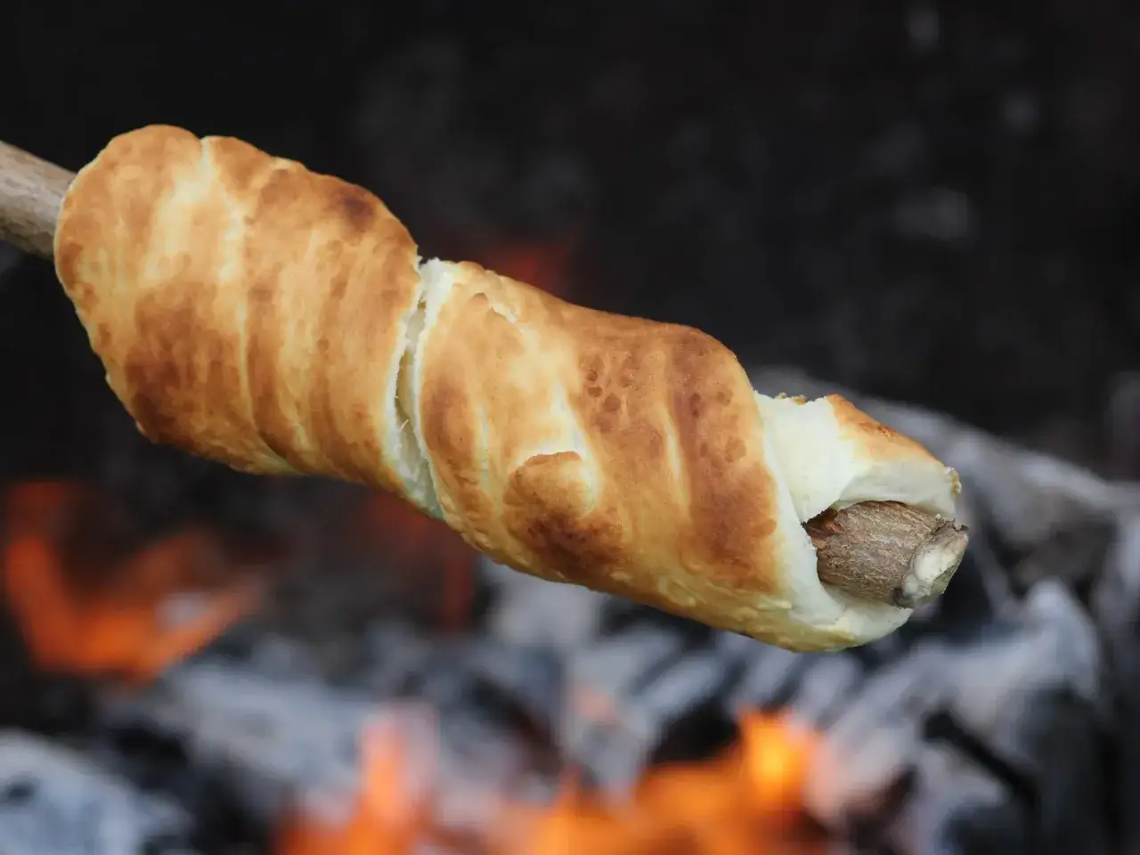 Złocisty chlebek pieczony na patyku nad ogniskiem, idealne szybkie przekąski na ognisko.
