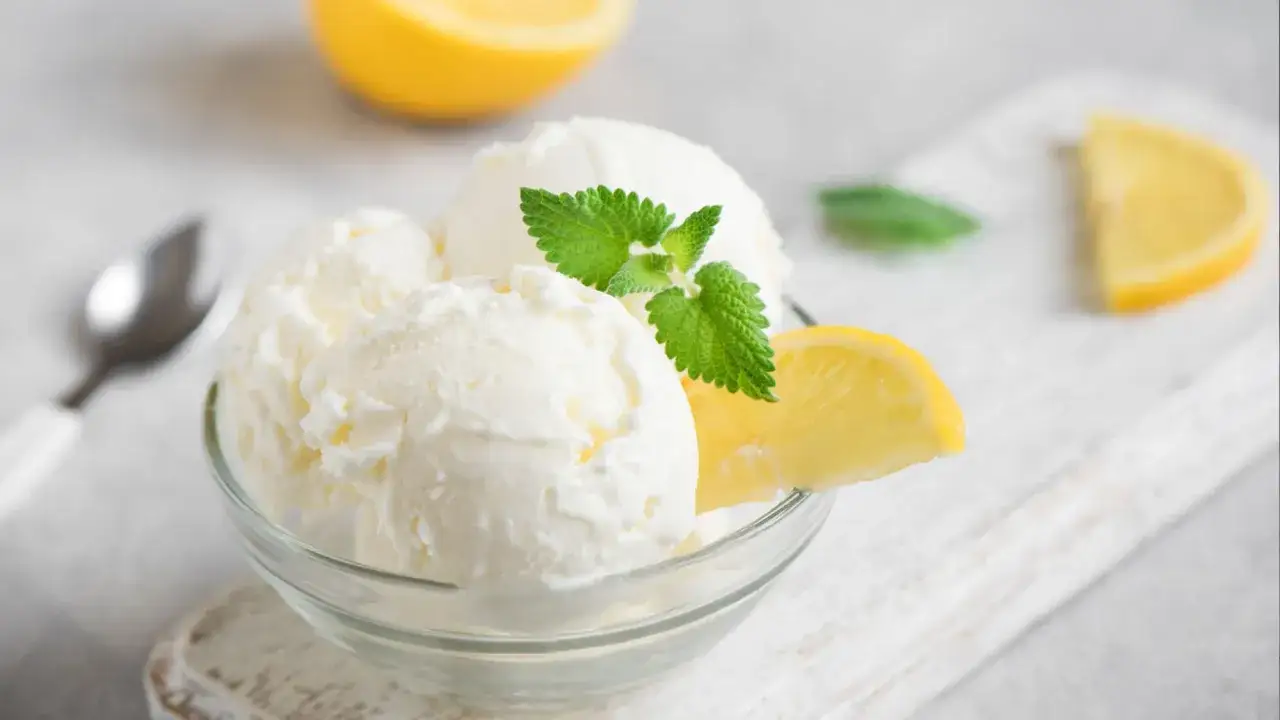 Schüssel mit cremigem Buttermilch Zitronen Eis, garniert mit Minze und Zitronenspalten. Erfrischend und lecker!