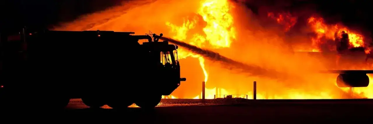 Camion de pompiers luttant contre un incendie d&eacute;vastateur, rappelant les dangers des catastrophes technologiques.