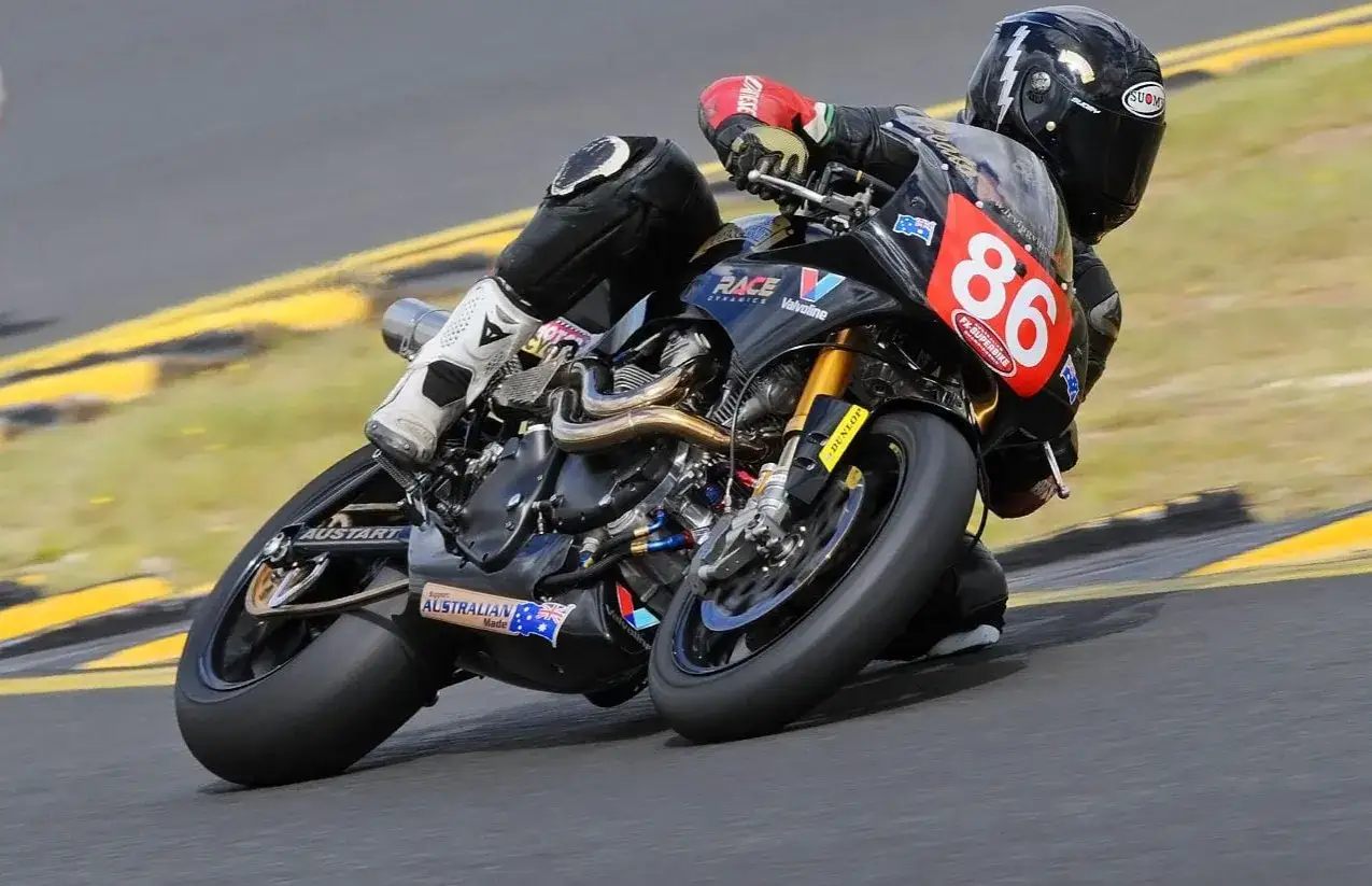 Piloto Irving Vincent inclinado en curva, número 86 en su moto de competición negra.
