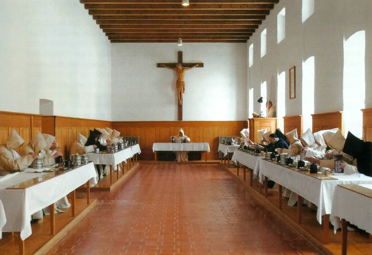 M&ouml;nche in Kapuzenm&auml;nteln speisen im Refektorium der Kartause Marienau. Ein Kruzifix h&auml;ngt an der Wand.