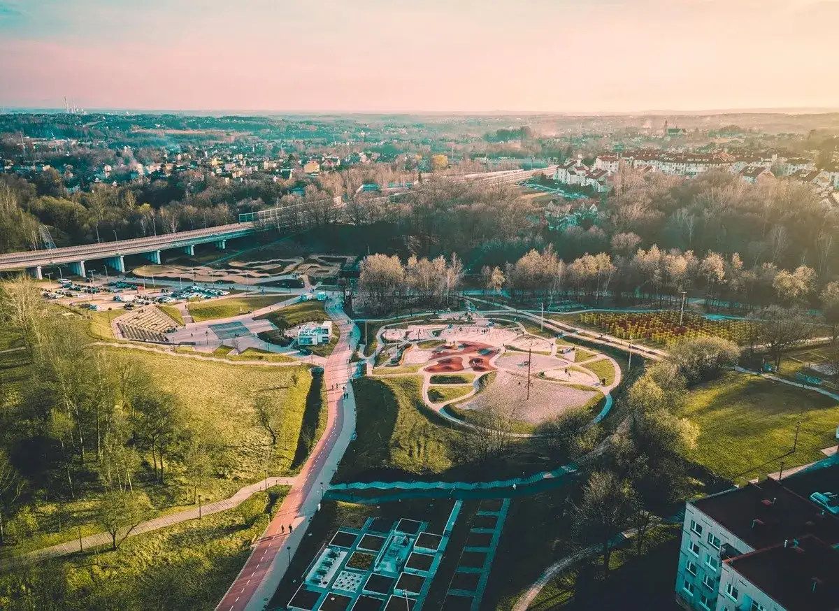 Widok z lotu ptaka na rodzinny park rozrywki Trzy Wzgórza z placem zabaw, ścieżkami i zielenią.