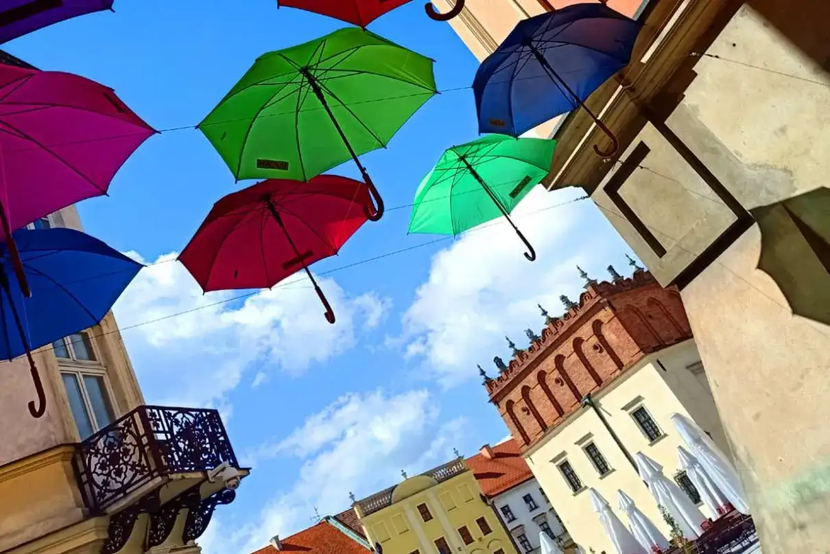 Kolorowe **tarnowskie parasolki** wiszą nad urokliwą uliczką, tworząc radosną atmosferę.
