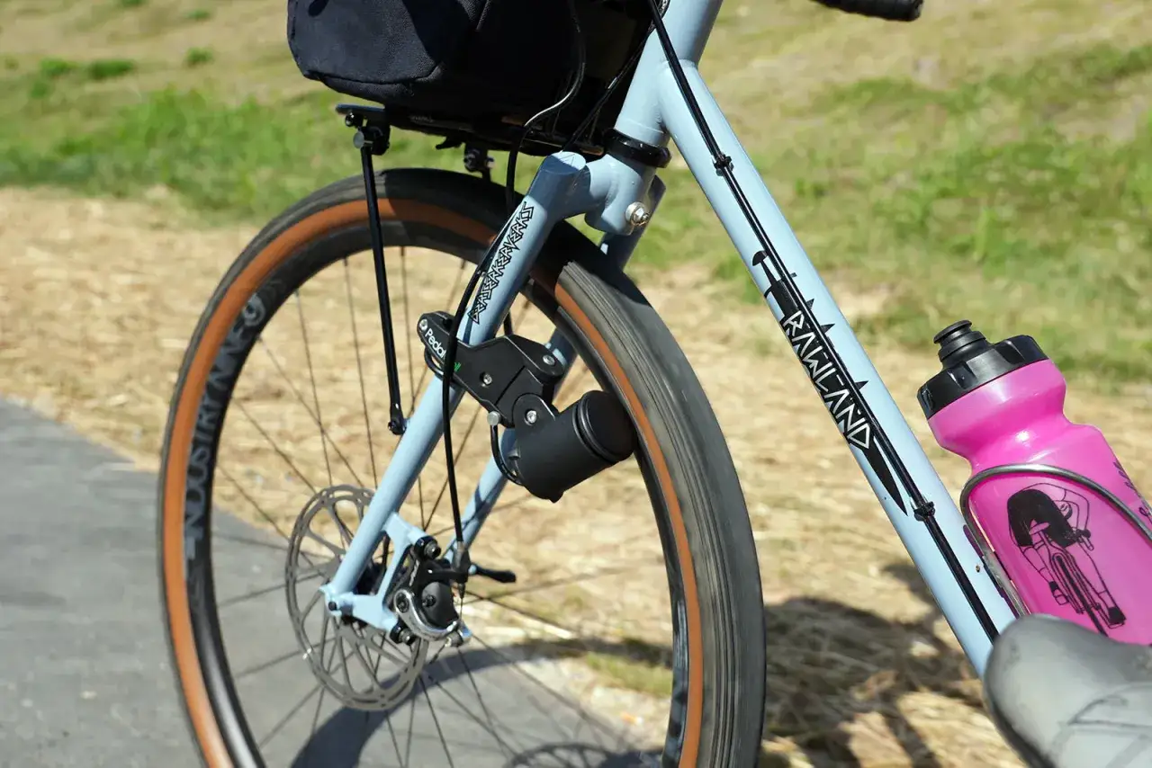Rowerowa przygoda zasilana przez dynamo. Czarny, kompaktowy dynamo do roweru zamontowany przy przednim kole, gotowy do ładowania sprzętu w trasie.