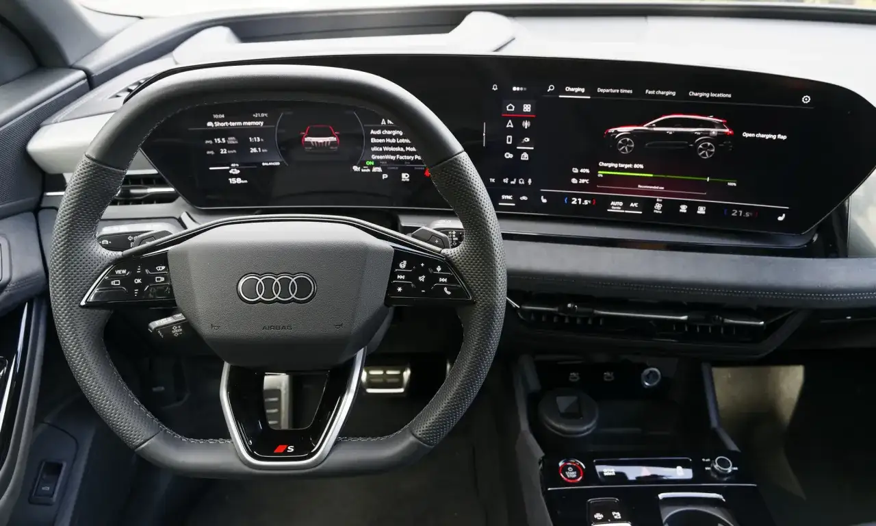 Wnętrze Audi SQ6 z cyfrowymi zegarami i ekranem multimediów pokazującym ładowanie.