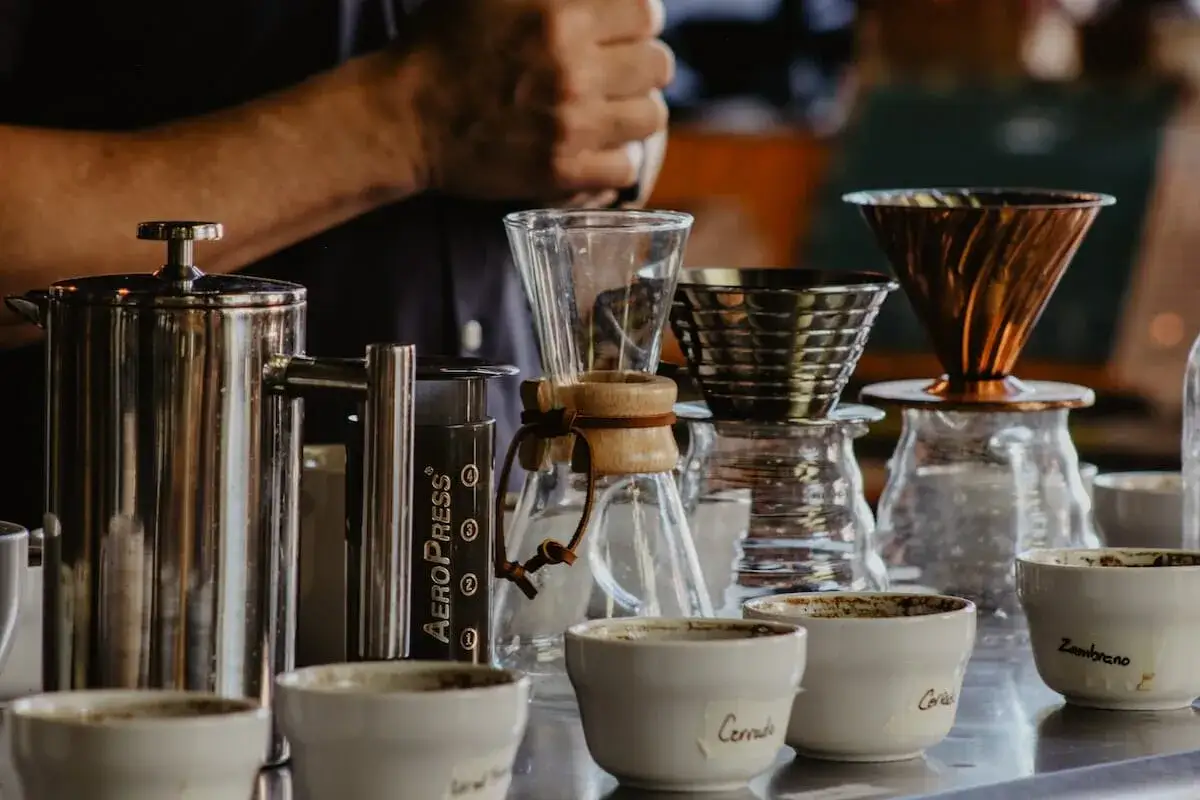 Przygotowanie do tego, jak zrobić pyszną kawę: french press, AeroPress, dripper i filiżanki czekają na zaparzenie.