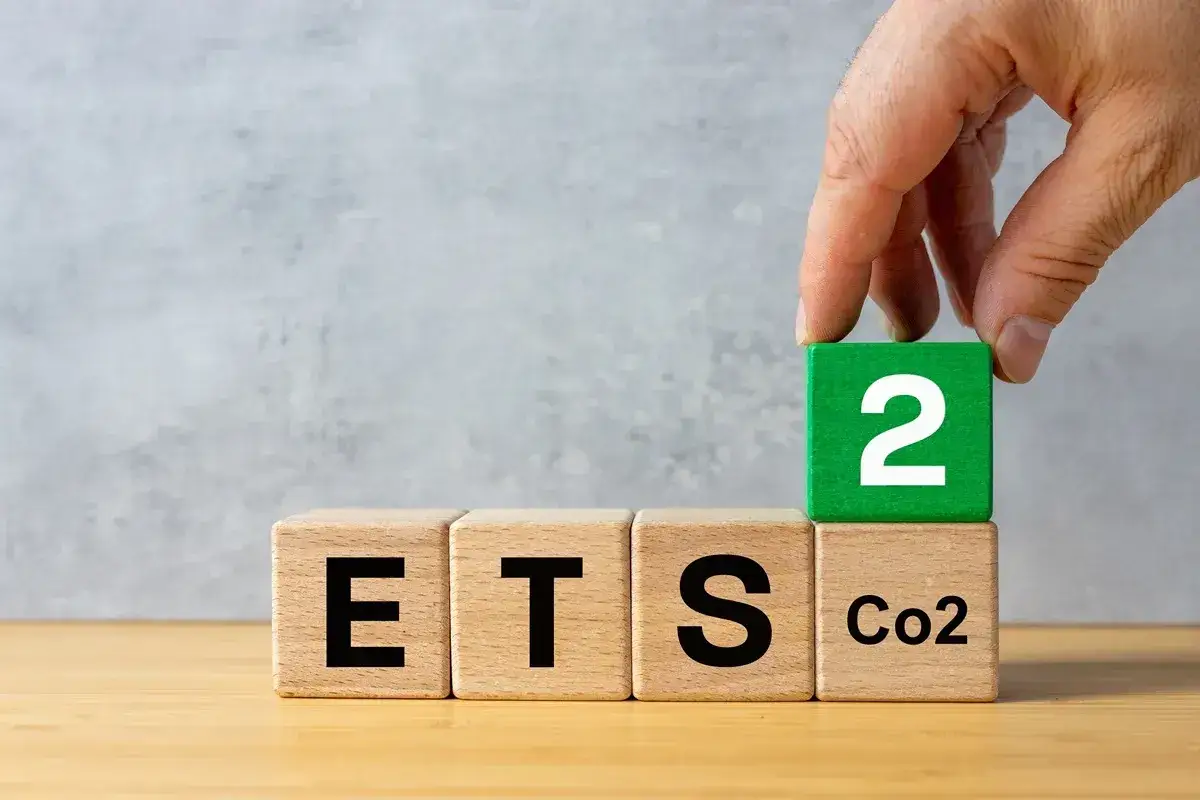 Ręka układa kostki z napisami ETS, CO2 i cyfrą 2. Symbolizuje to nowy etap w systemie handlu emisjami, czyli podatek emisyjny.