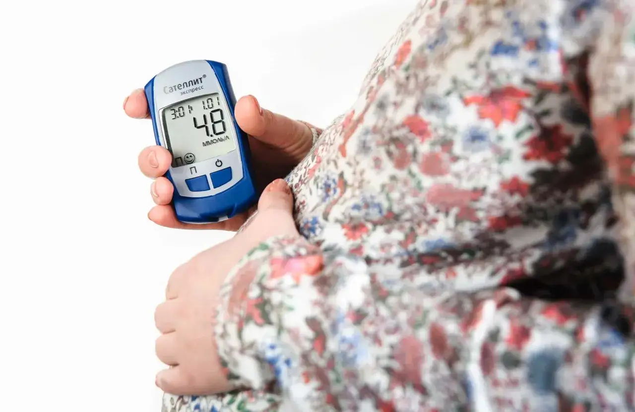 Gravid kvinna kontrollerar blodsockret med en glukosmätare. En viktig del av att hantera gravid diabetes.