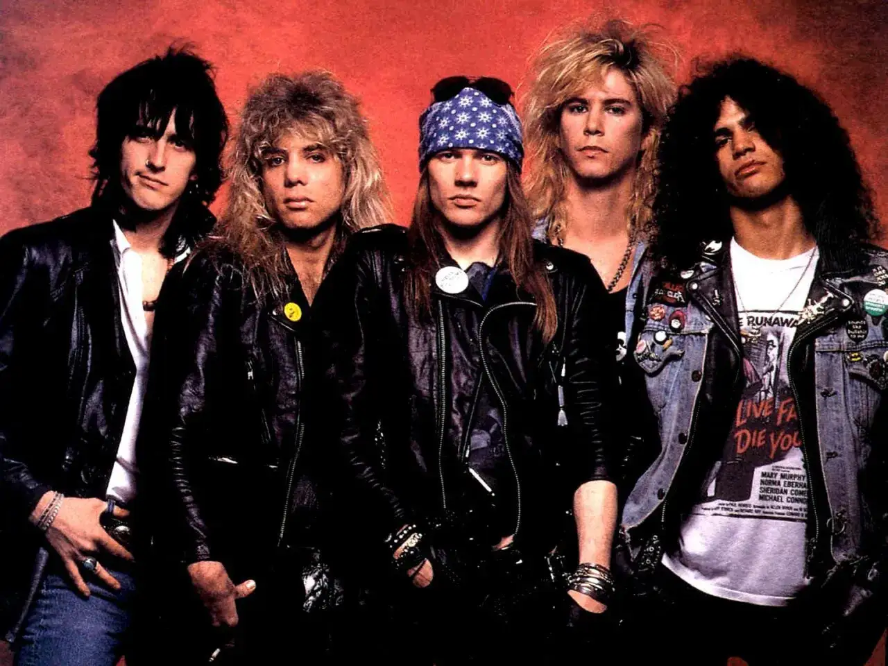Guns N' Roses członkowie w skórzanych kurtkach i dżinsach, z charakterystycznymi fryzurami i dodatkami.
