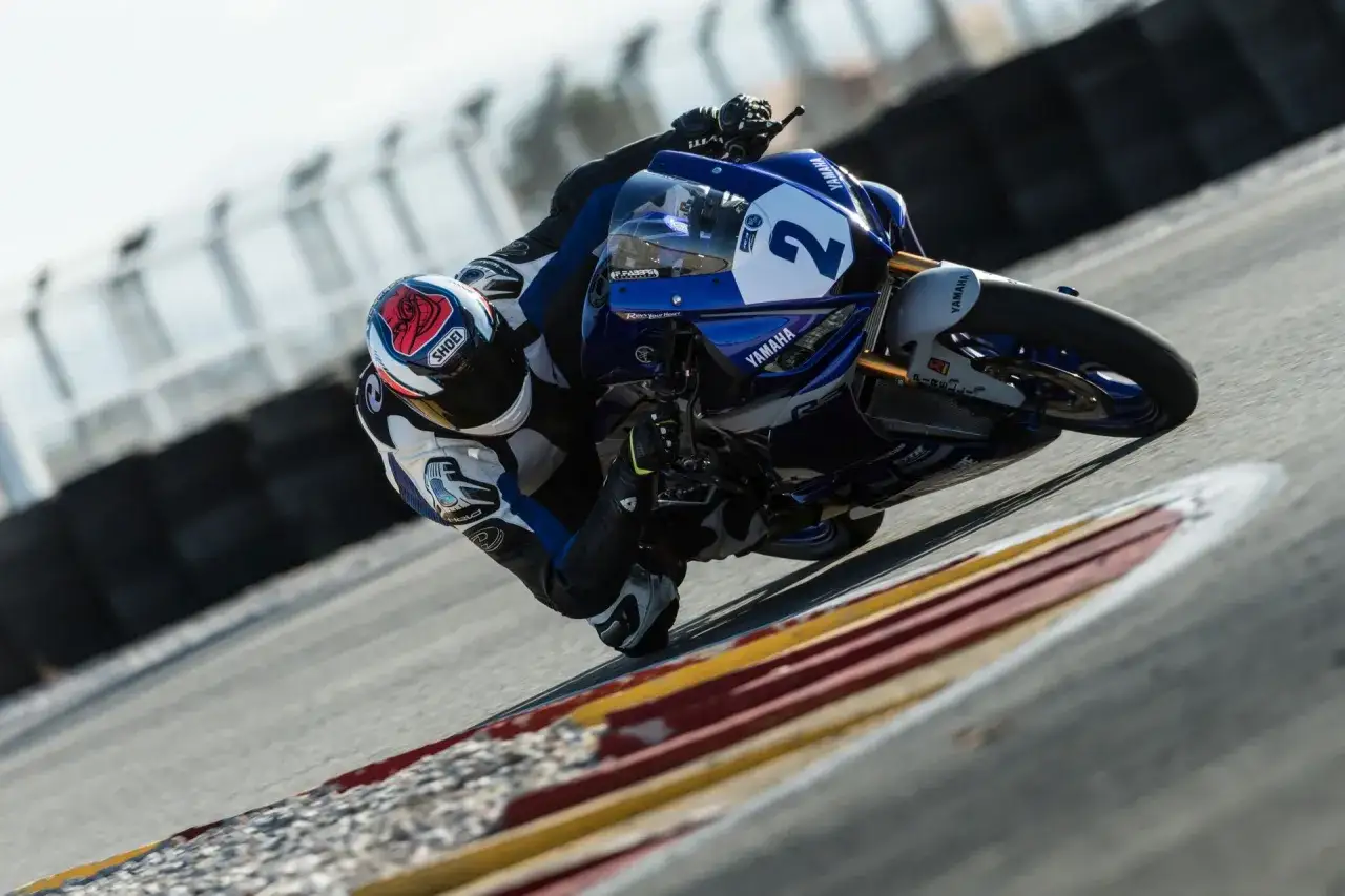 Motocyklista pochyla się na zakręcie, pokazując dynamiczny sport motocyklowy.