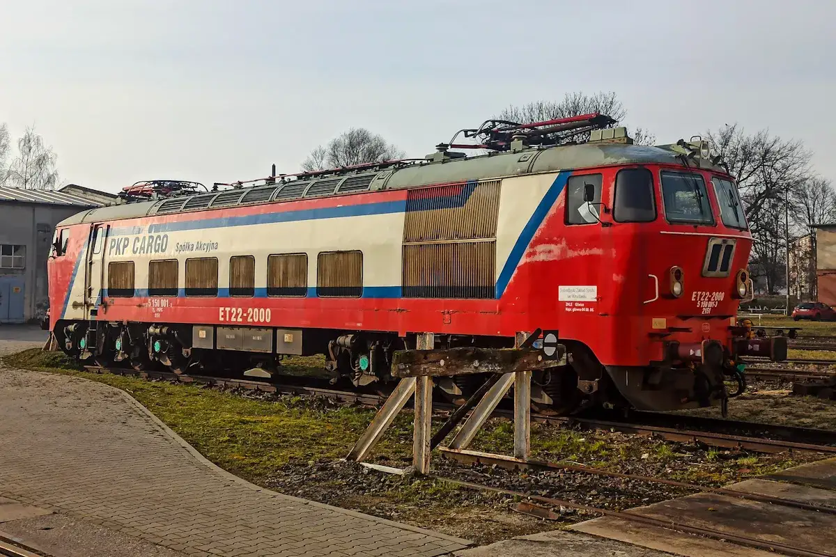 Czerwono-biało-niebieska lokomotywa PKP Cargo ET22-2000 stoi na torach.