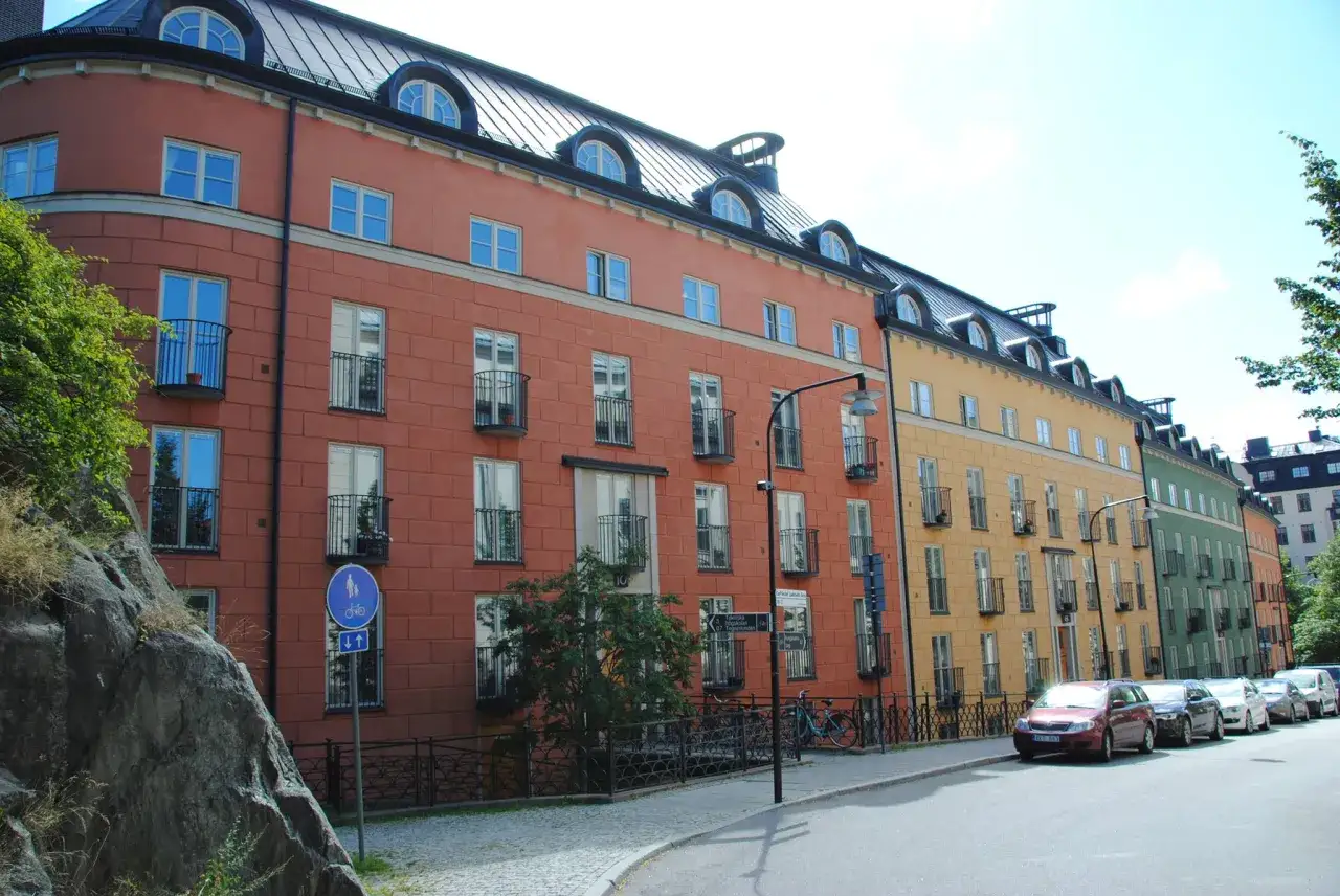 Färgglada hus längs en gata i Stockholm, **Nordens Aten**, med cyklar och bilar parkerade.