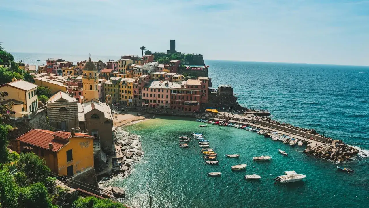 Vue pittoresque de Vernazza, un village color&eacute; accroch&eacute; &agrave; la falaise, o&ugrave; se trouve la Riviera Italienne. Des bateaux flottent dans la baie aux eaux turquoise.