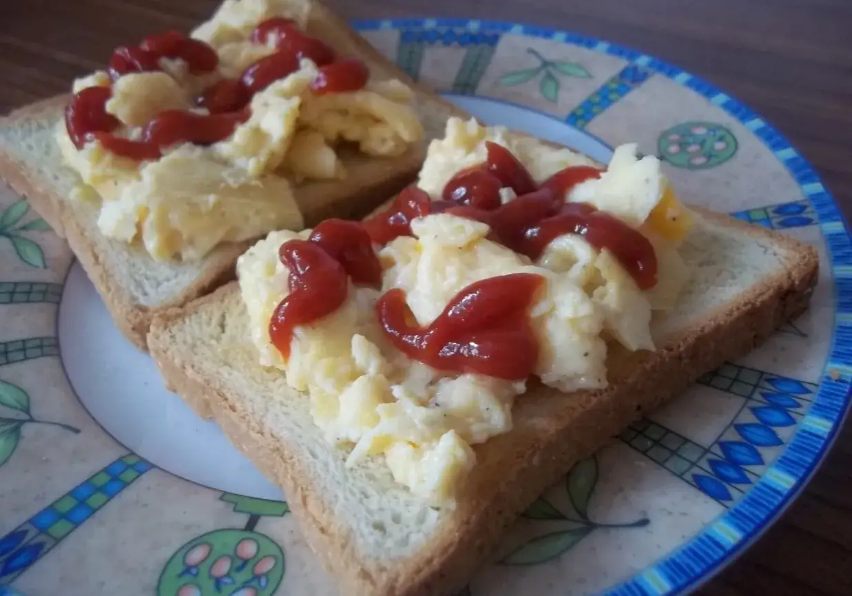 Szybkie śniadanie na ciepło: jajecznica na tostach z keczupem. Idealne na poranek, gdy liczy się każda minuta.