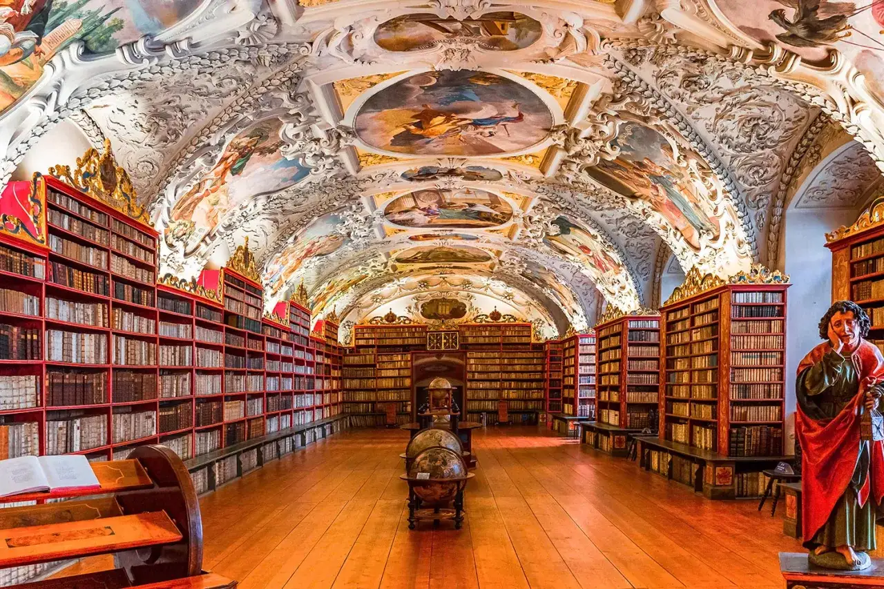 Biblioth&egrave;que du monast&egrave;re de Strahov, avec ses &eacute;tag&egrave;res remplies de livres anciens, ses fresques baroques au plafond et ses globes terrestres.