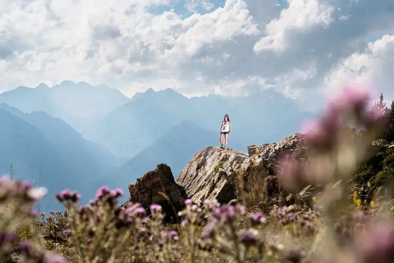 Una mujer en la cima de una monta&ntilde;a rocosa, disfrutando de las vistas. &iexcl;Una gran idea de qu&eacute; hacer en Cerler en verano!