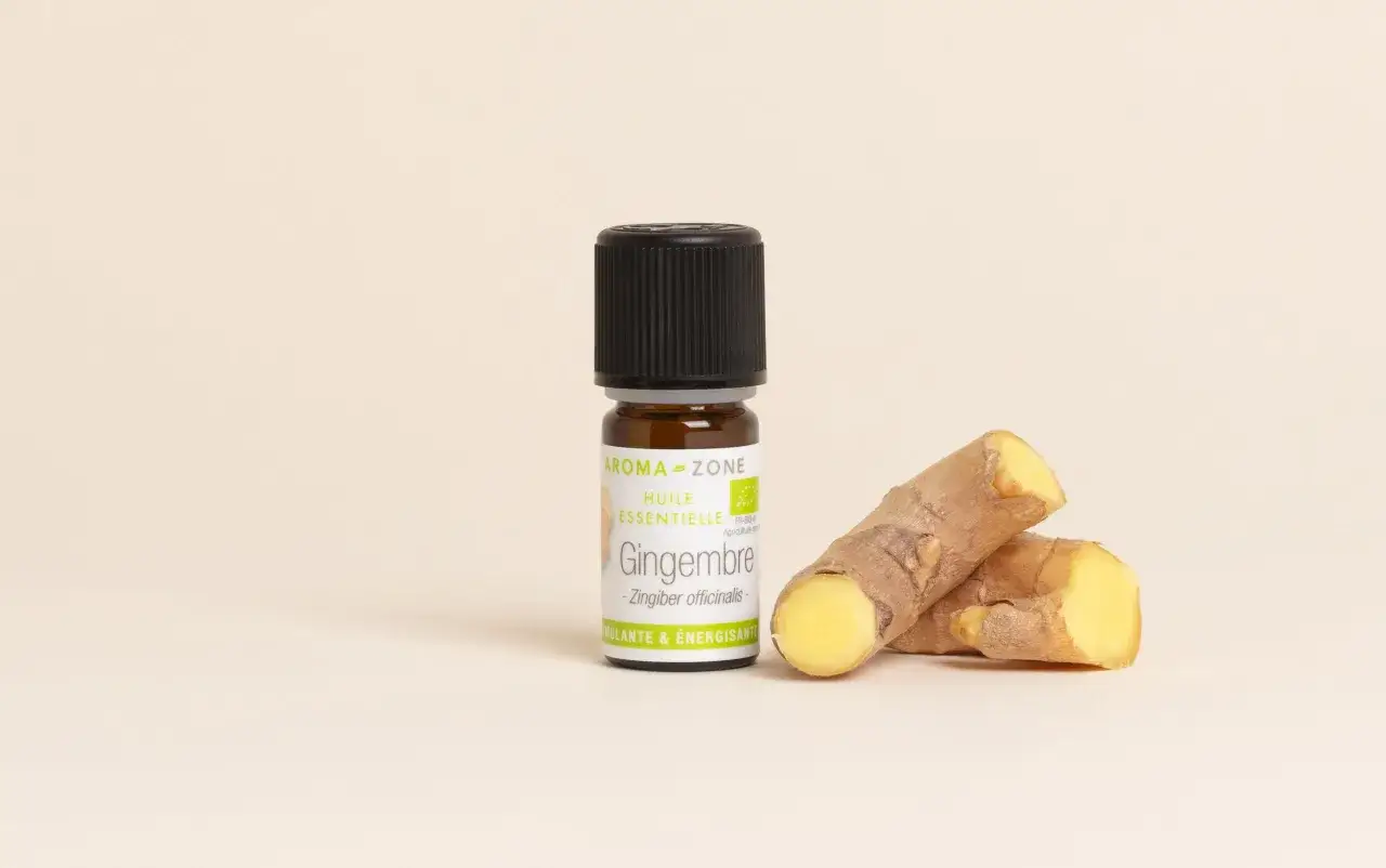Flacon d'huile essentielle de gingembre bio, aux côtés de racines de gingembre frais. Un concentré de vitalité et d'énergie.