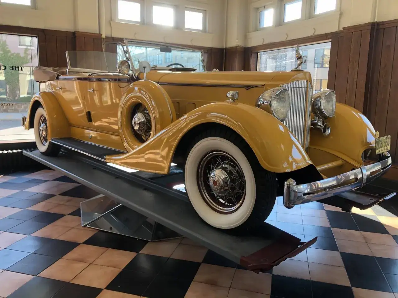 En gul Packard bil, en klassisk sk&ouml;nhet med vita d&auml;cksidor, st&aring;r p&aring; en ramp.