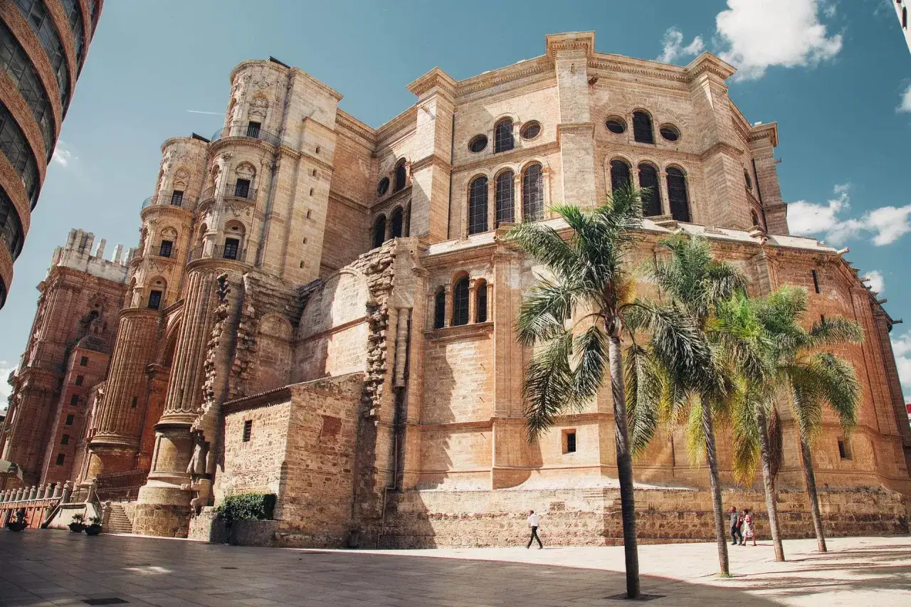 La Catedral de Málaga, uno de los imprescindibles de Málaga, se alza majestuosa con sus torres y palmeras.