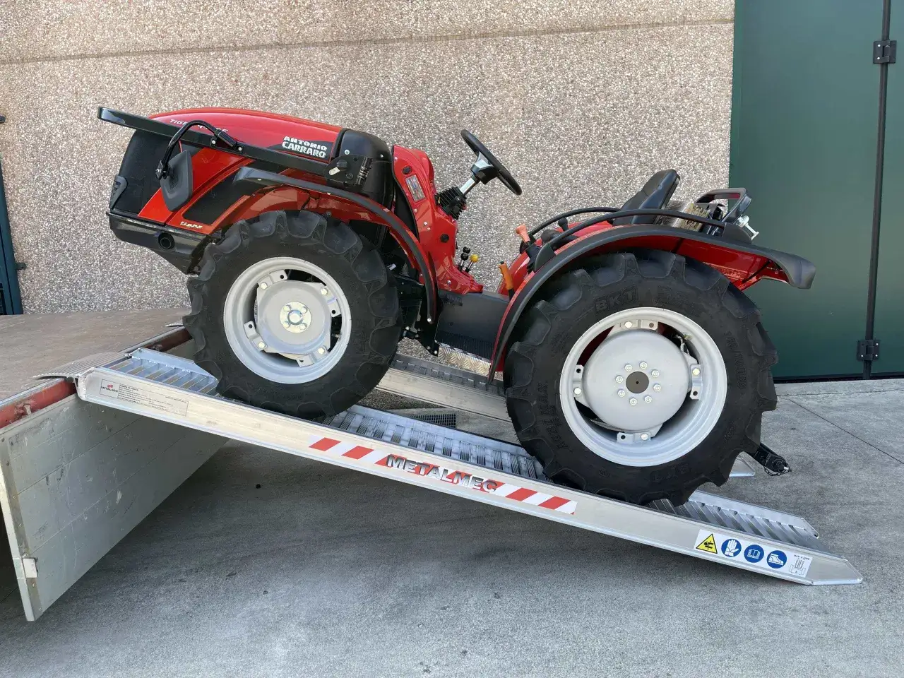 Roter Traktor f&auml;hrt auf stabile Auffahrrampen 2t.