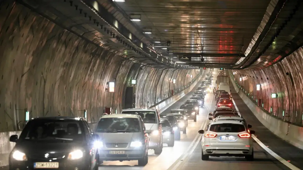 Korek samochodów w tunelu w Świnoujściu. Długi, kręty tunel z oświetleniem i wyłożonymi ścianami.
