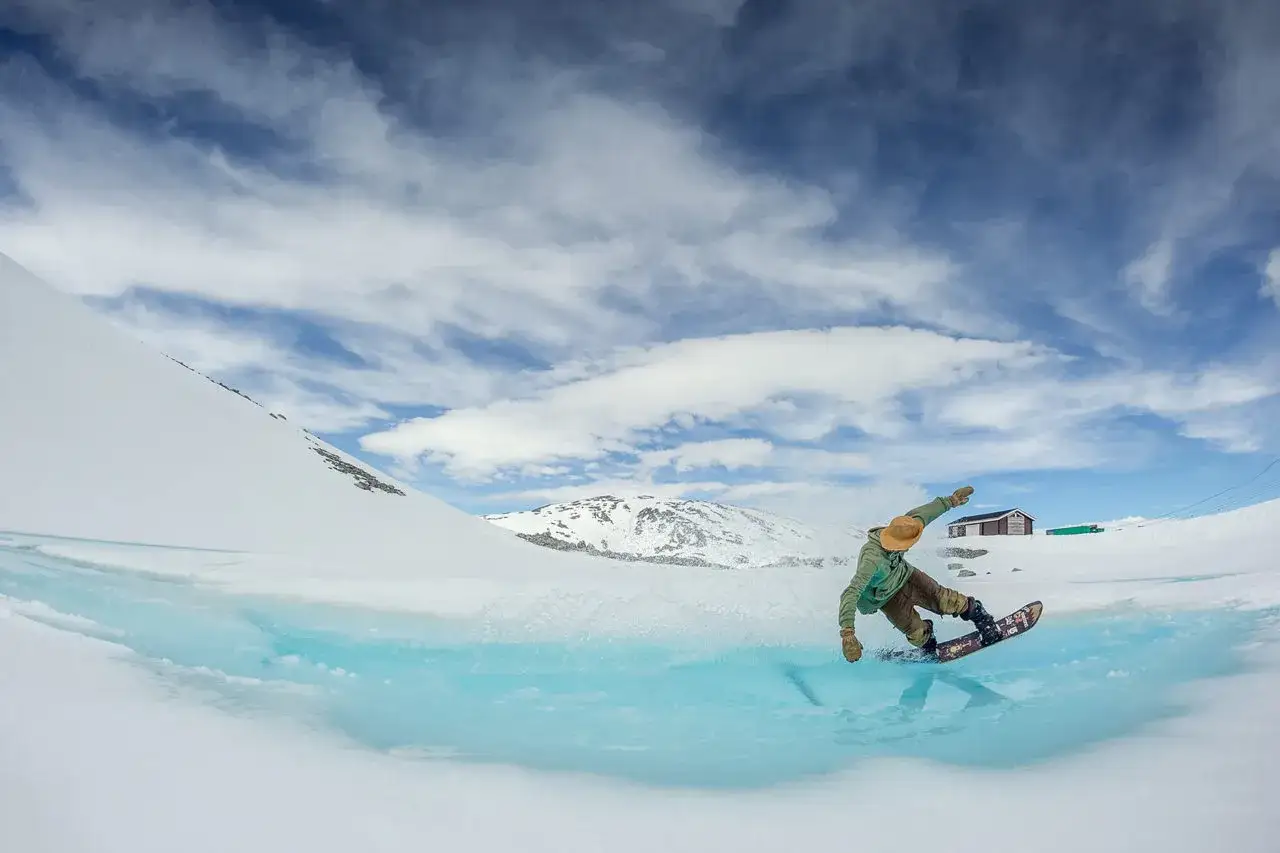 En snowboardåkare gör en sväng över en isig sjö i Norge, en perfekt dag för sommarskidåkning.
