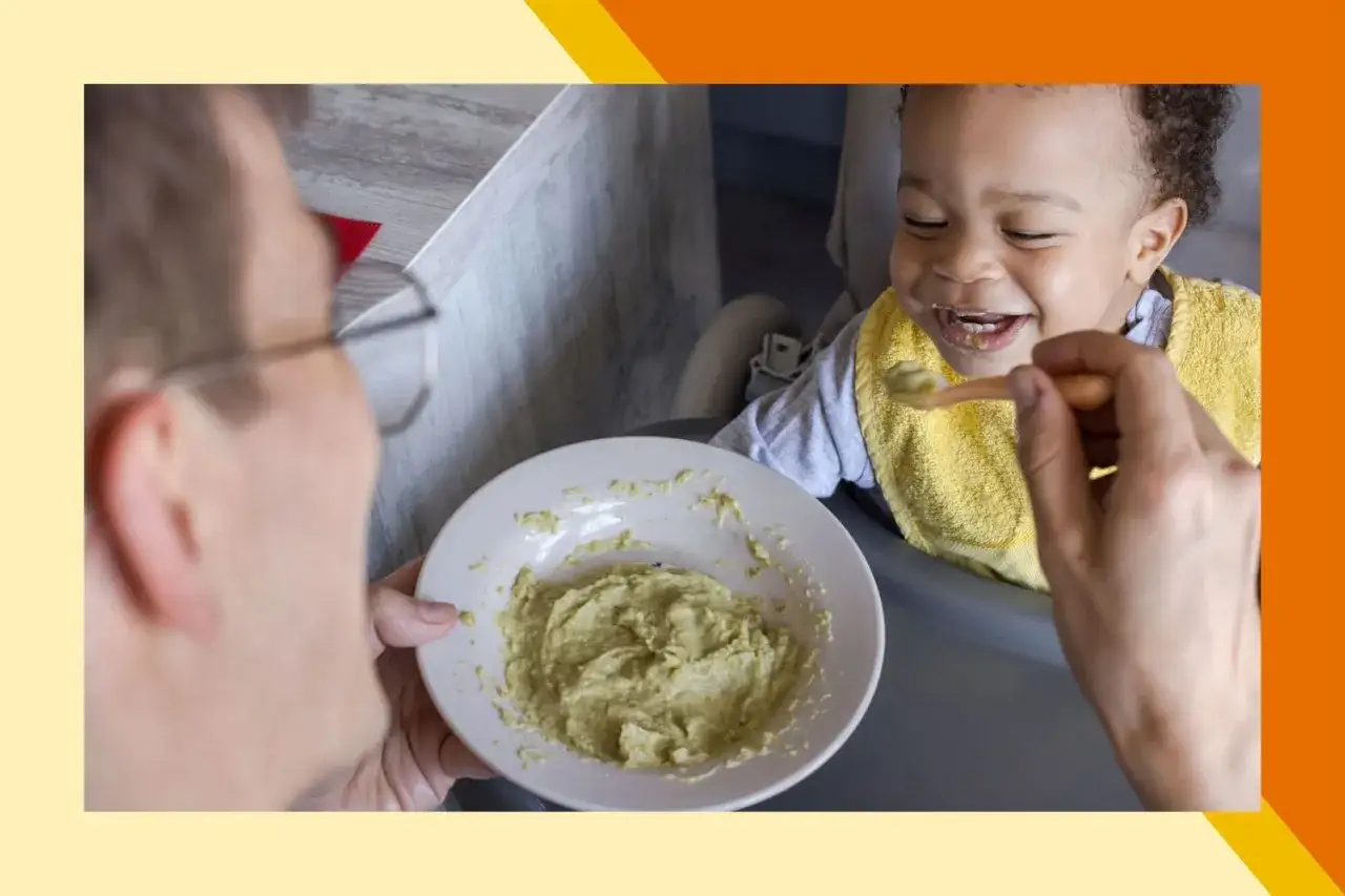 Uśmiechnięty niemowlak w żółtym śliniaku dostaje łyżeczkę z zielonym puree. To pierwsze próby jedzenia, może to być nawet masło orzechowe dla niemowlaka.