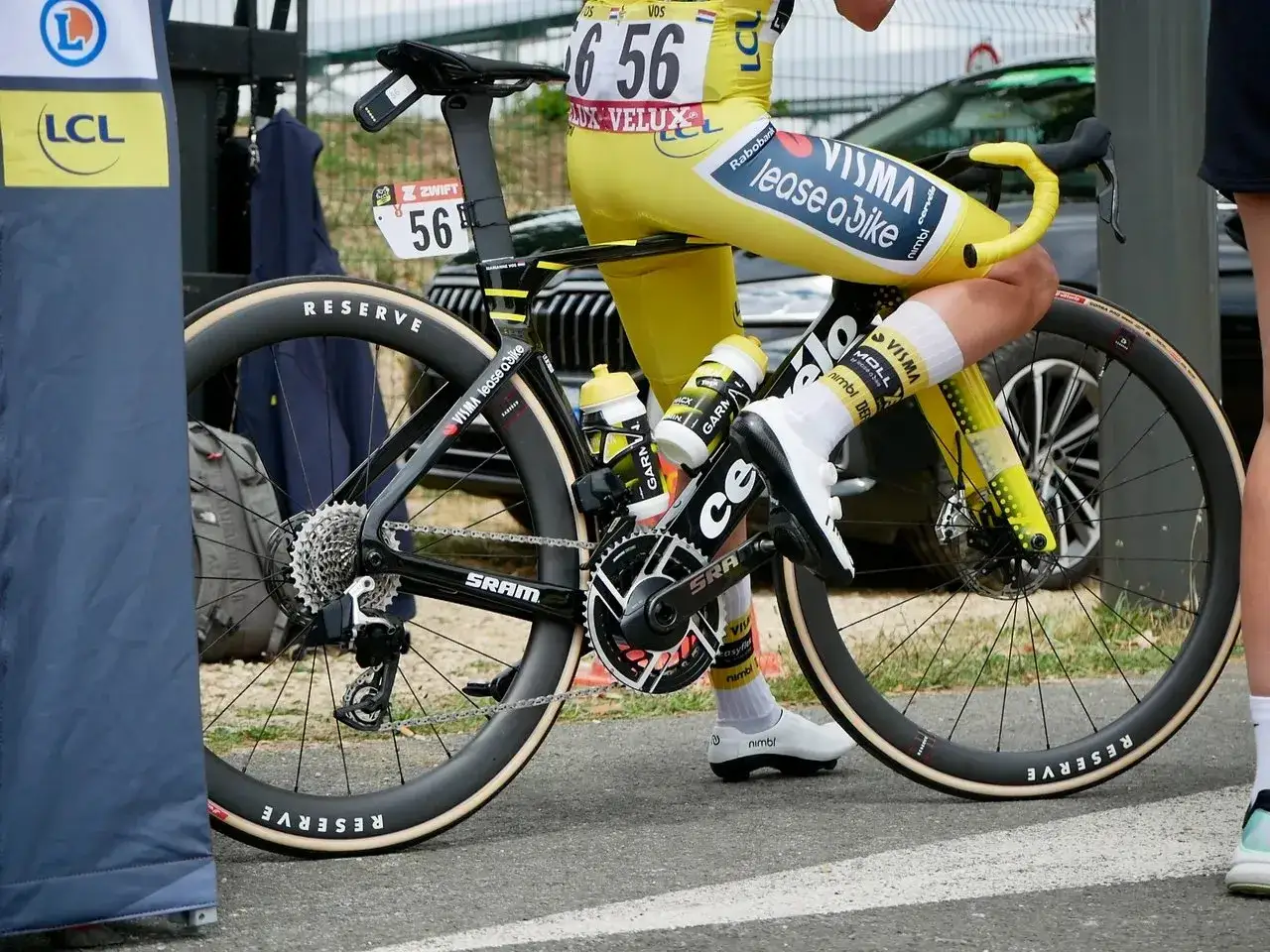Marianne Vos im gelben Trikot, bereit für die nächste Etappe. Ihr Rennrad mit SRAM-Schaltung und Reserve-Felgen.