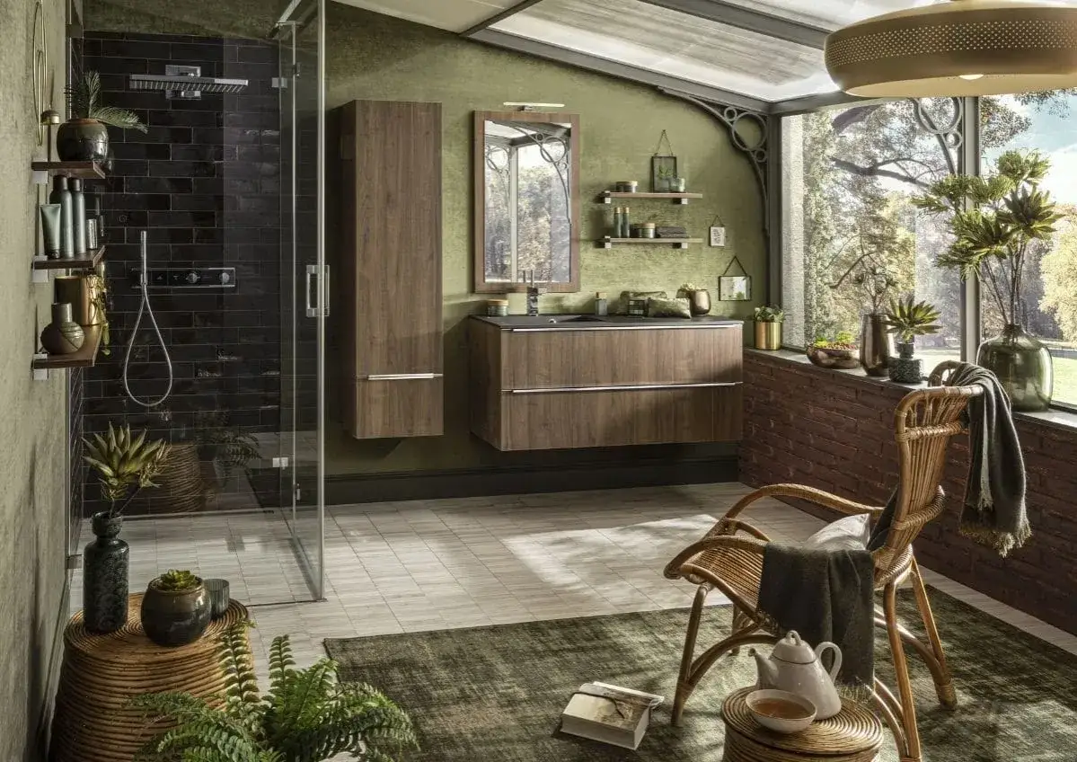 Une **salle de bain verte** avec une douche moderne, des meubles en bois, un fauteuil en rotin et une vue sur la nature.