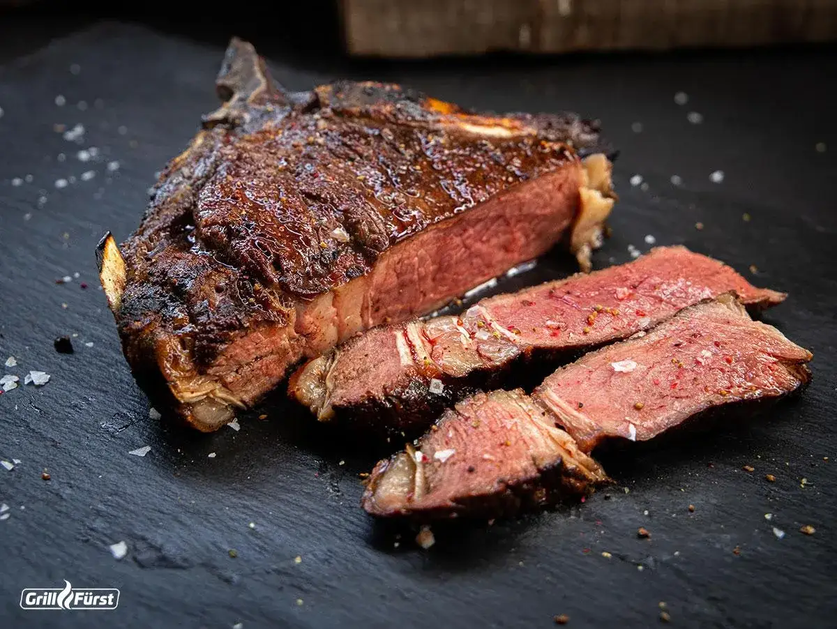 Perfekt gegrilltes C&ocirc;te de Boeuf, saftig und medium-rare, mit grobem Salz und Pfeffer bestreut.