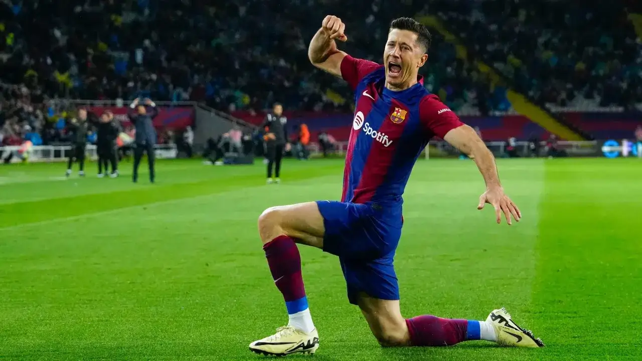Piłkarz FC Barcelony świętuje hat trick, klęcząc na boisku z uniesioną ręką.