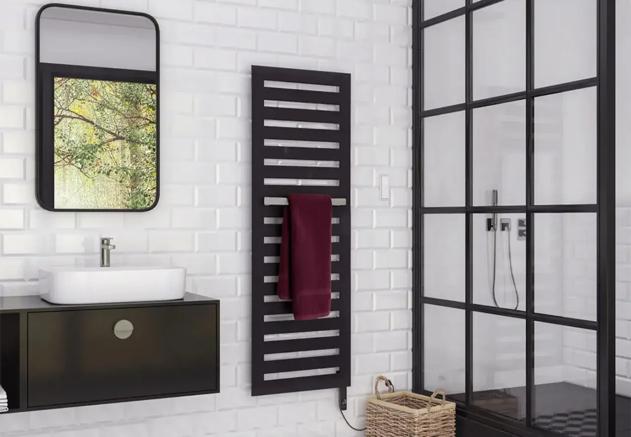 Radiador toallero negro moderno con toalla burdeos, junto a un espejo y ducha.