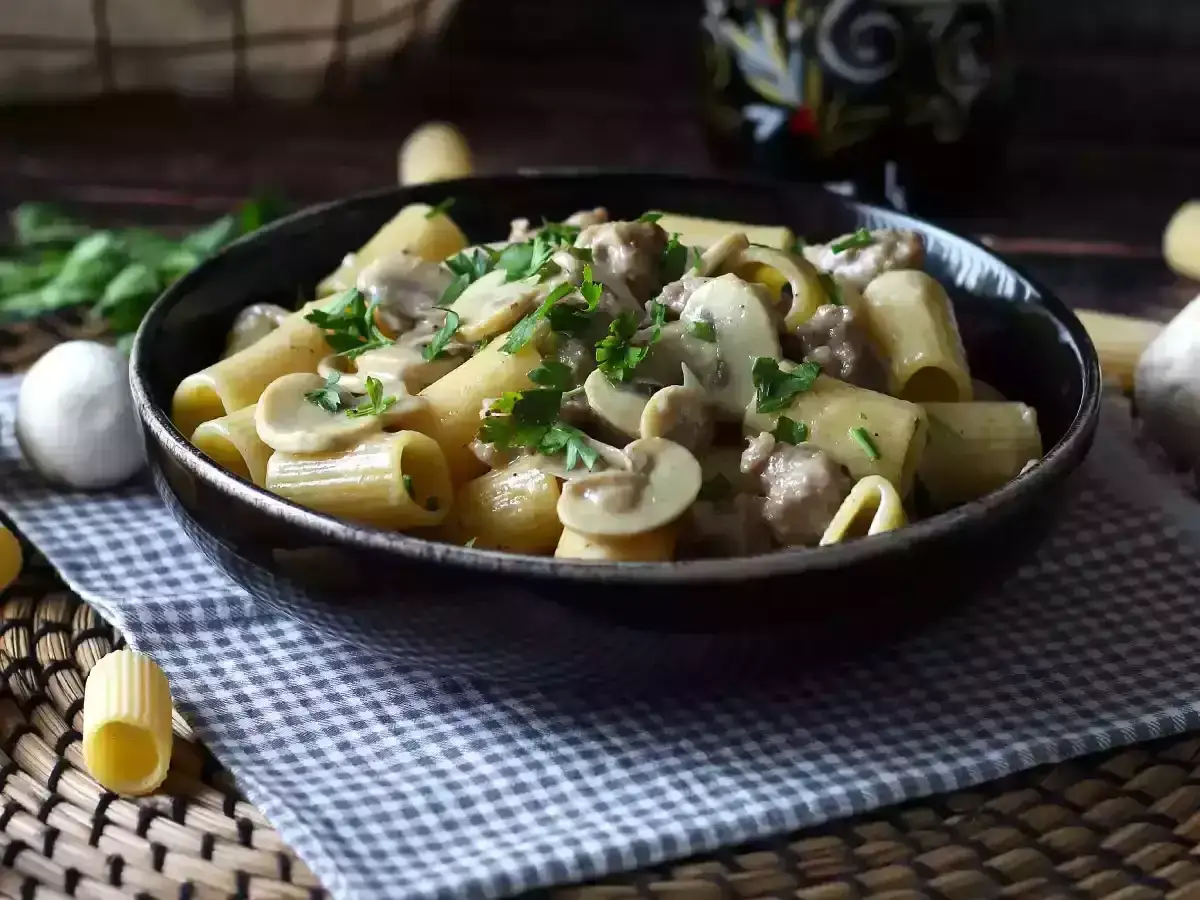 Pyszny makaron z pieczarkami w kremowym sosie, posypany świeżą natką pietruszki. Idealny na szybki obiad.